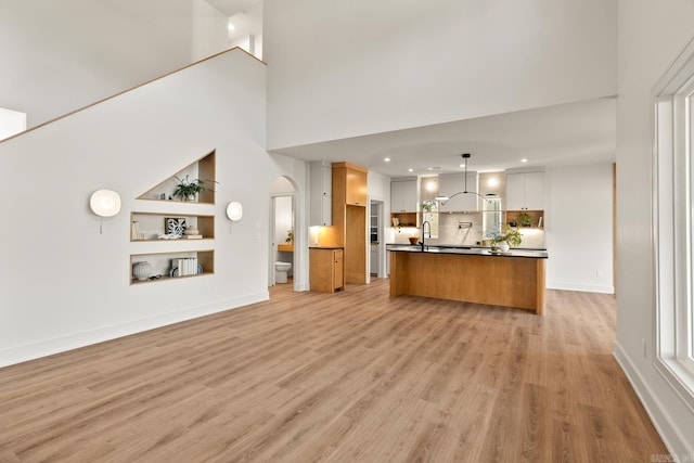 unfurnished living room featuring baseboards, a sink, and light wood-style floors