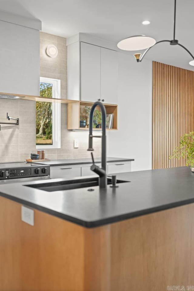 kitchen with dark countertops, backsplash, and range with electric stovetop