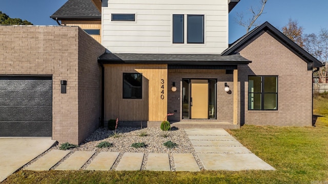 view of front of property with an attached garage, brick siding, roof with shingles, and a front yard