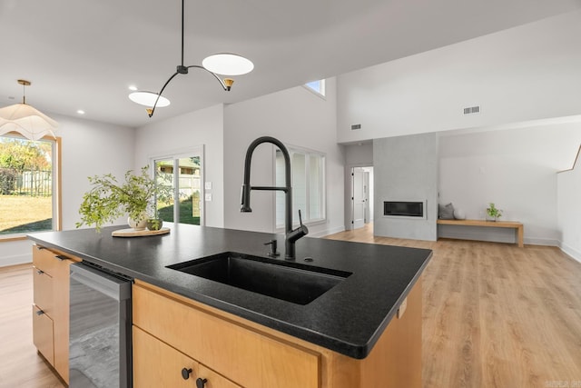 kitchen with light wood-style floors, a fireplace, visible vents, and a sink