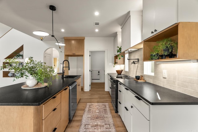 kitchen with dark countertops, tasteful backsplash, arched walkways, and a sink