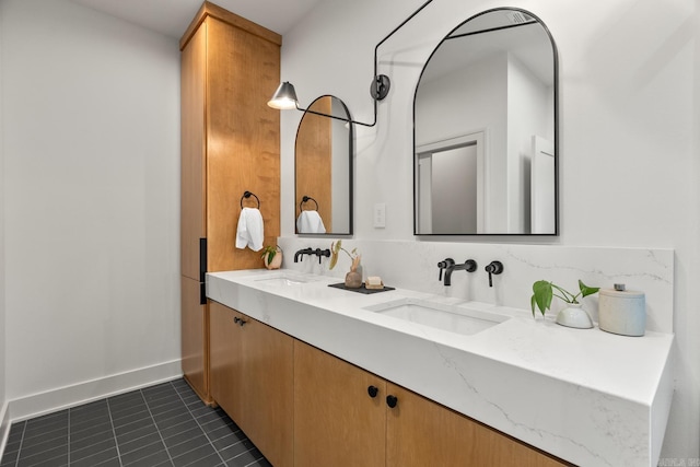 bathroom with baseboards, double vanity, a sink, and tile patterned floors