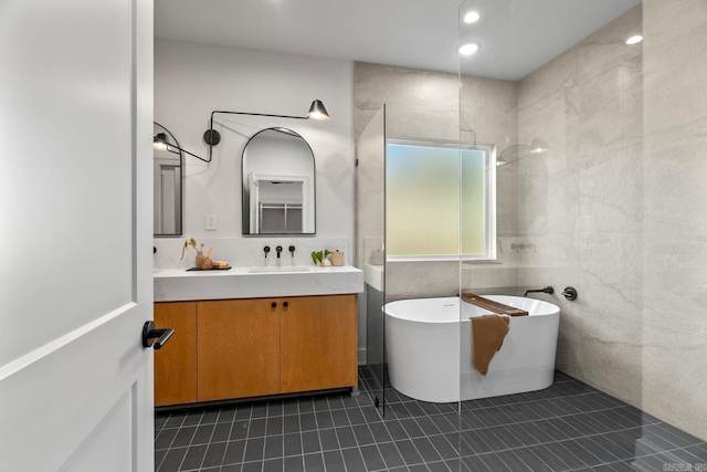 full bathroom with tile walls, recessed lighting, a soaking tub, vanity, and tile patterned flooring