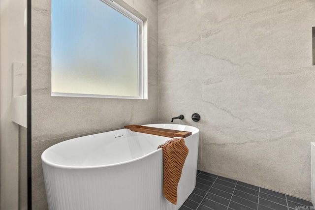 full bathroom featuring a freestanding tub, tile walls, and tile patterned floors