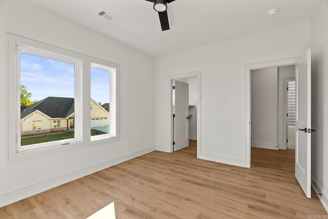 unfurnished bedroom featuring visible vents, baseboards, a ceiling fan, light wood-style flooring, and a spacious closet