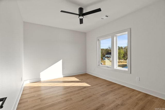 spare room featuring a ceiling fan, visible vents, baseboards, and wood finished floors