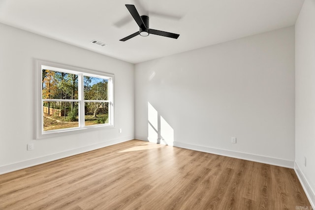 unfurnished room with a ceiling fan, wood finished floors, visible vents, and baseboards