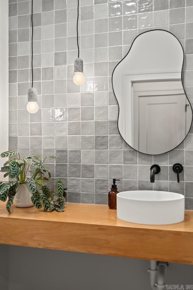 bathroom with backsplash, a sink, and tile walls