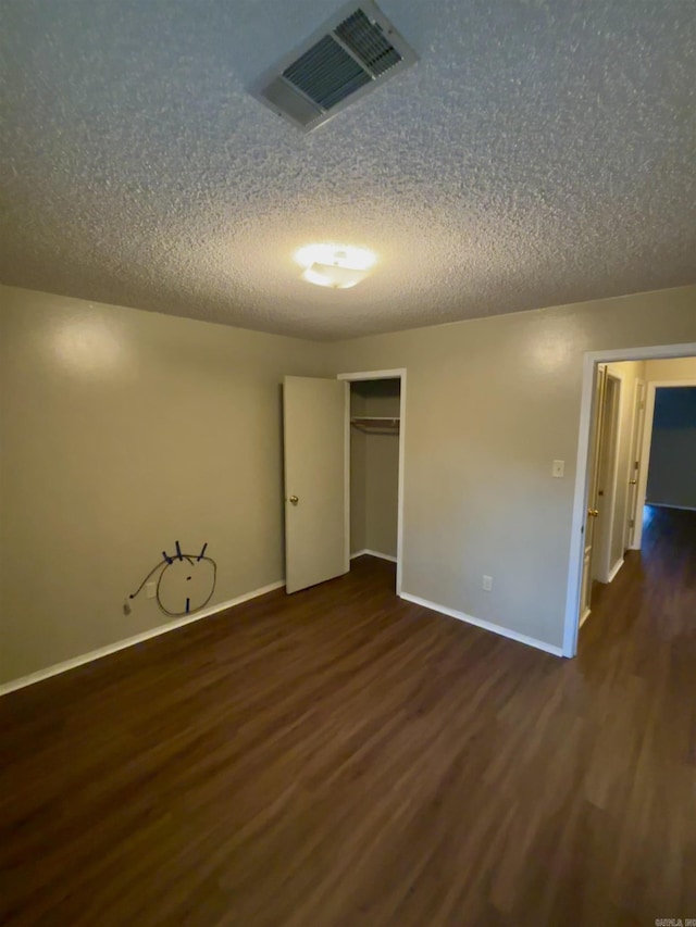 unfurnished room with visible vents, a textured ceiling, and wood finished floors