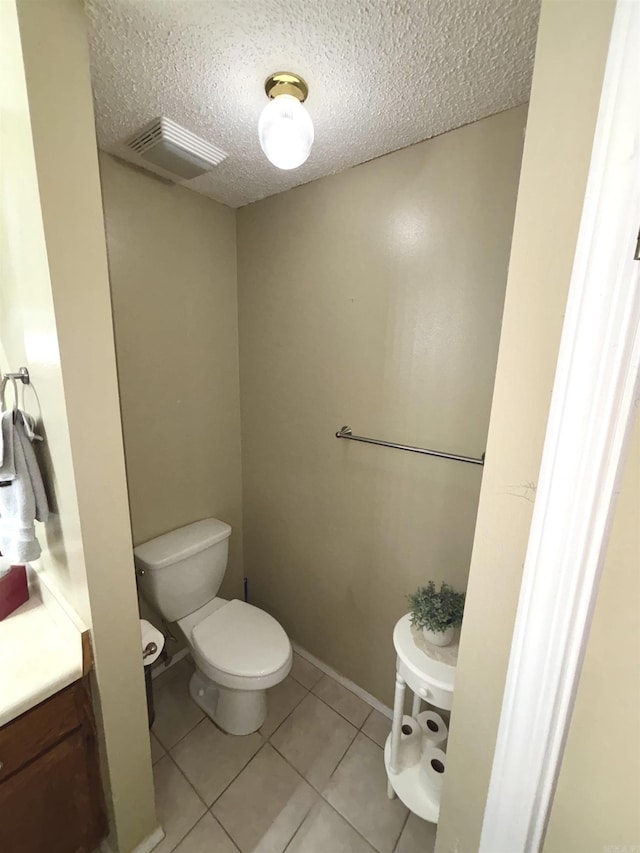 half bathroom featuring visible vents, toilet, tile patterned flooring, a textured ceiling, and vanity