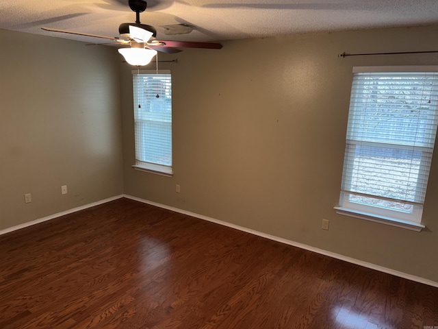 empty room featuring dark wood finished floors, a textured ceiling, baseboards, and ceiling fan