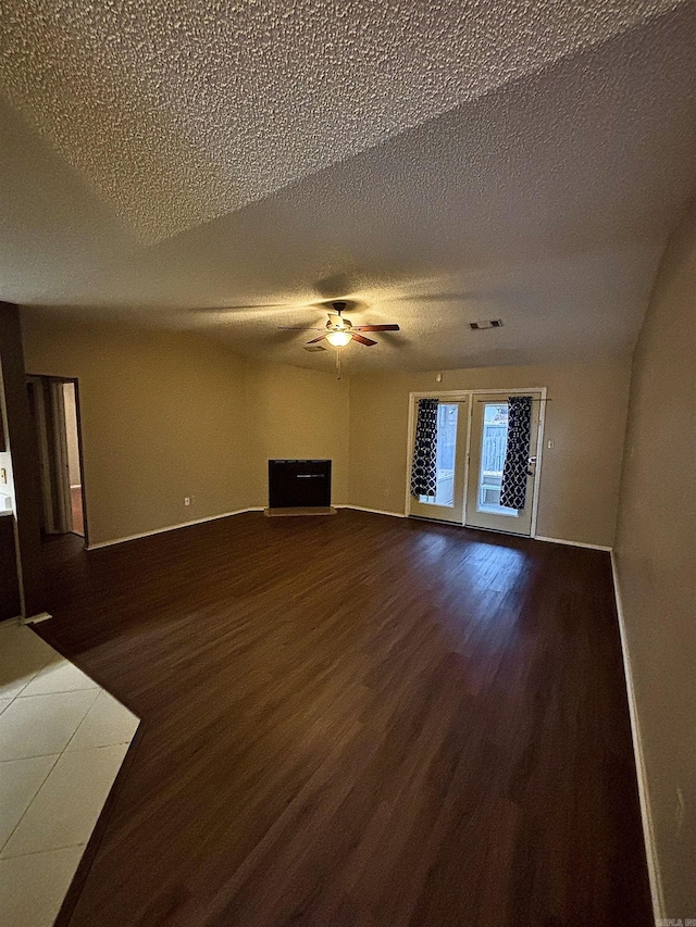 unfurnished living room featuring ceiling fan, dark wood finished floors, visible vents, and baseboards