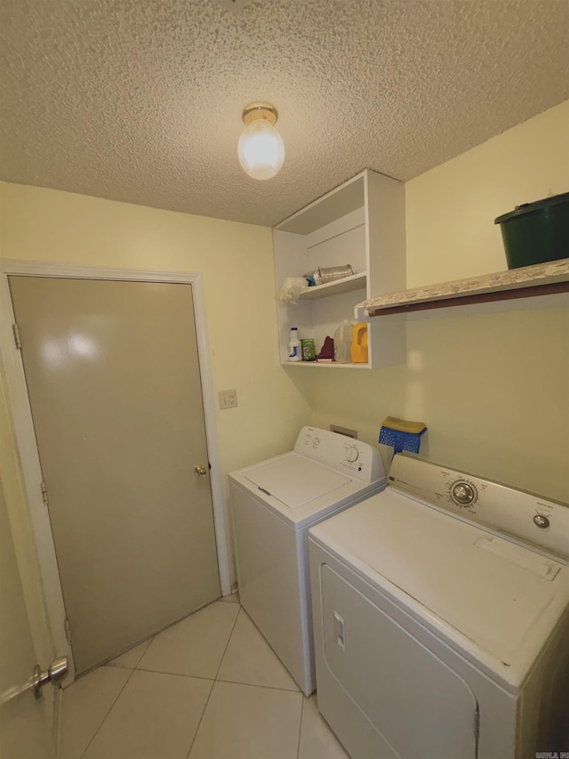 washroom with light tile patterned floors, laundry area, a textured ceiling, and washing machine and clothes dryer