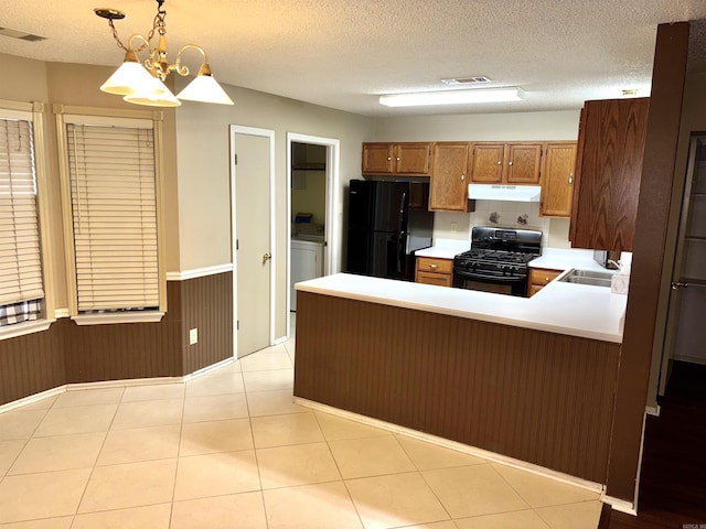 kitchen with under cabinet range hood, a peninsula, a sink, visible vents, and black appliances