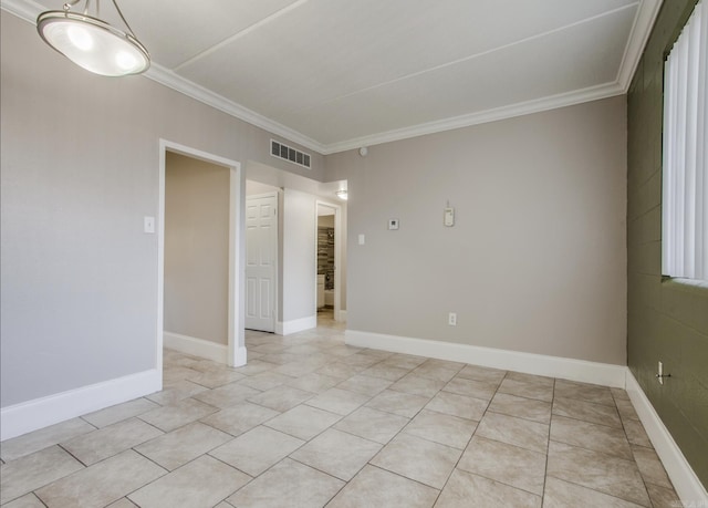 empty room featuring baseboards, visible vents, and crown molding