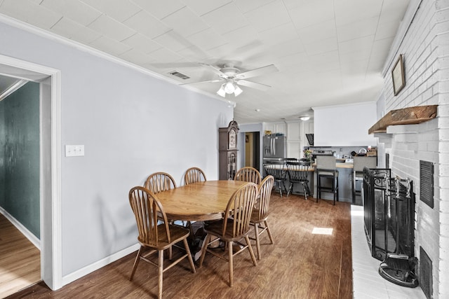 dining room featuring ornamental molding, a ceiling fan, visible vents, and wood finished floors