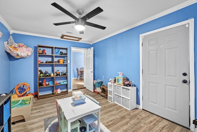 recreation room with crown molding, wood finished floors, visible vents, and attic access