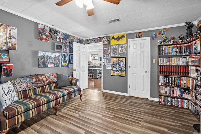 living area with baseboards, visible vents, a ceiling fan, ornamental molding, and wood finished floors