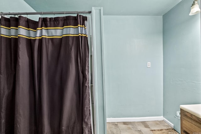 bathroom with a shower with curtain, vanity, and baseboards