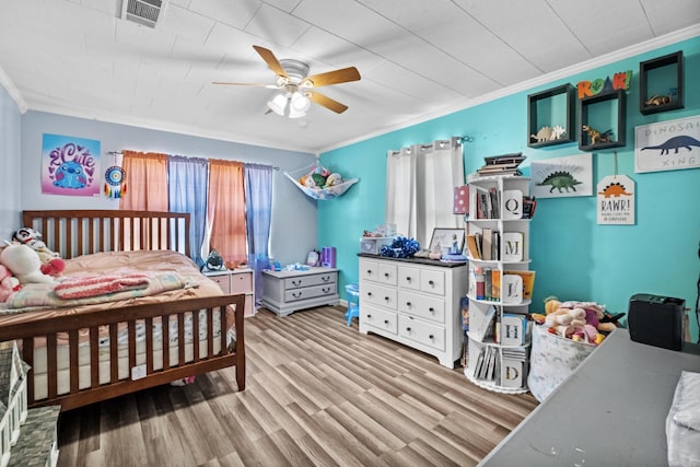 bedroom with crown molding, visible vents, ceiling fan, and wood finished floors