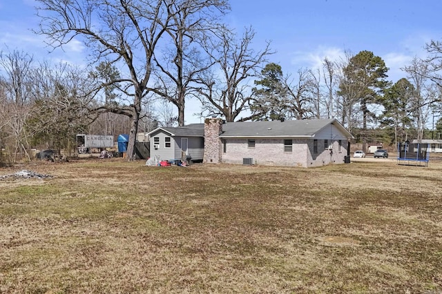 back of property with a trampoline, a lawn, and central air condition unit