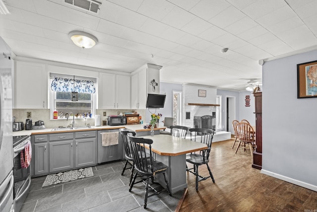 kitchen with visible vents, appliances with stainless steel finishes, gray cabinetry, a fireplace, and a sink