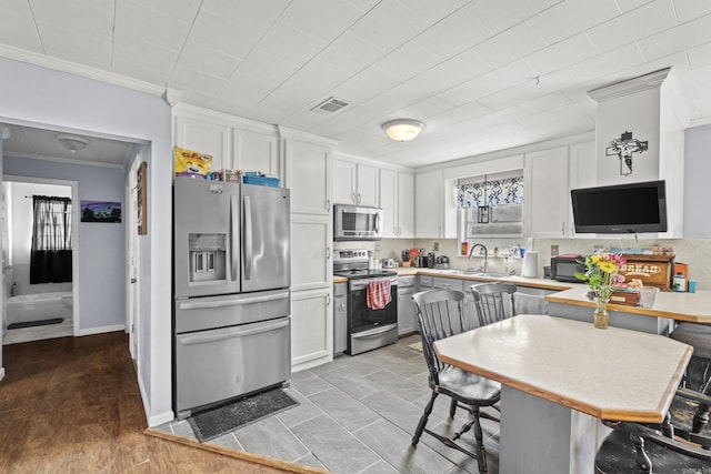 kitchen with stainless steel appliances, visible vents, white cabinetry, ornamental molding, and decorative backsplash