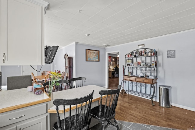 dining space featuring ornamental molding, dark wood finished floors, and baseboards