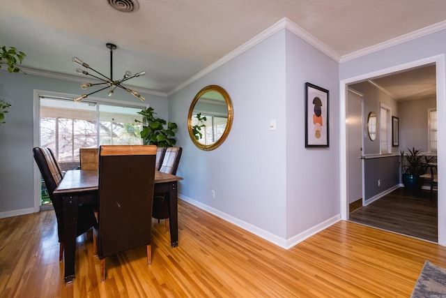 dining room featuring ornamental molding, light wood-type flooring, visible vents, and baseboards