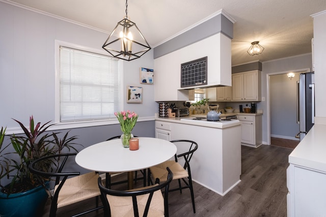 kitchen featuring white electric cooktop, dark wood-style floors, ornamental molding, freestanding refrigerator, and light countertops