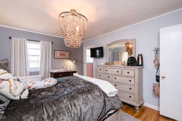 bedroom featuring baseboards, wood finished floors, an inviting chandelier, crown molding, and a textured ceiling