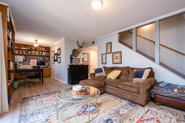 living area featuring crown molding, a textured ceiling, baseboards, and wood finished floors