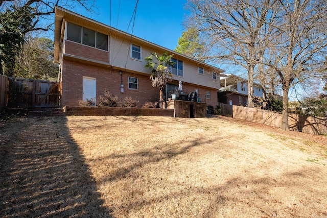 rear view of house featuring a gate, brick siding, and fence