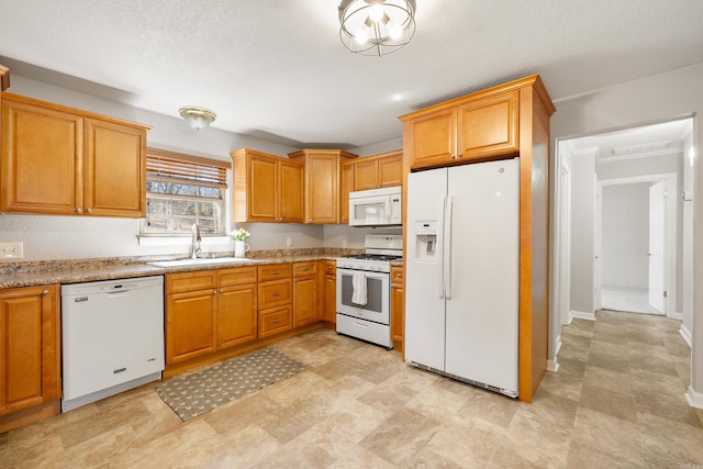 kitchen with white appliances, baseboards, and a sink