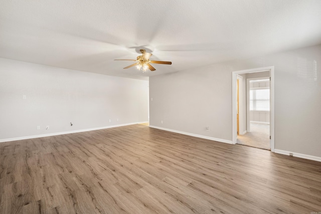 unfurnished room with wood finished floors, a ceiling fan, and baseboards