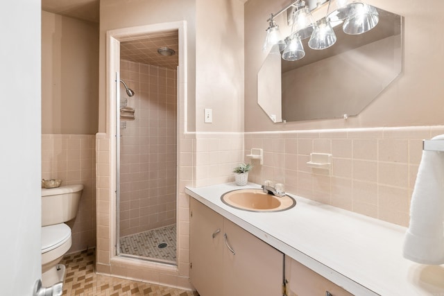 bathroom with a wainscoted wall, tile walls, toilet, a stall shower, and vanity