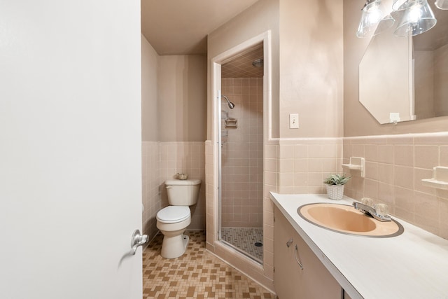 full bath featuring wainscoting, toilet, vanity, a shower stall, and tile walls