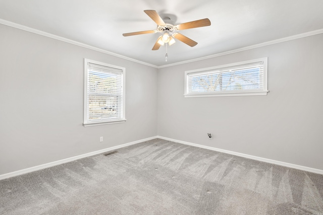 carpeted spare room with baseboards, ceiling fan, visible vents, and crown molding