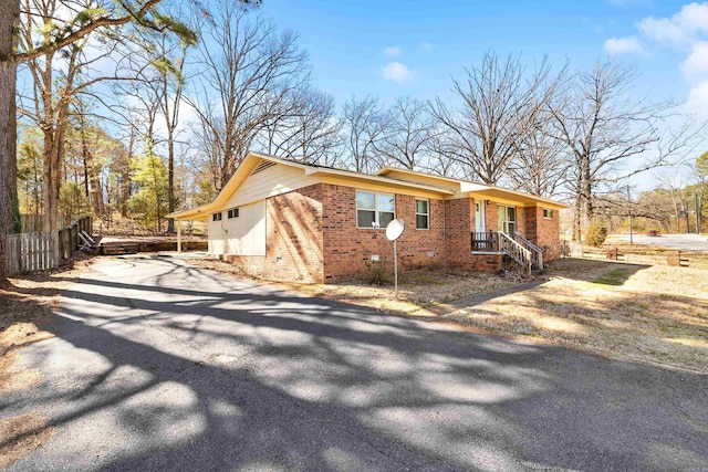 view of property exterior featuring crawl space, driveway, fence, and brick siding