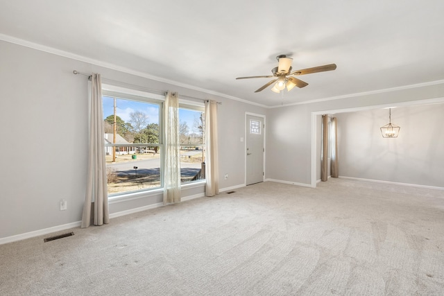 carpeted empty room featuring ornamental molding, visible vents, baseboards, and ceiling fan with notable chandelier