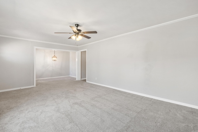 empty room featuring ceiling fan, carpet, baseboards, and crown molding