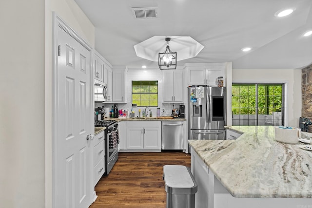 kitchen with dark wood finished floors, stainless steel appliances, visible vents, white cabinetry, and a sink