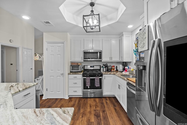 kitchen with visible vents, decorative backsplash, a raised ceiling, stainless steel appliances, and white cabinetry