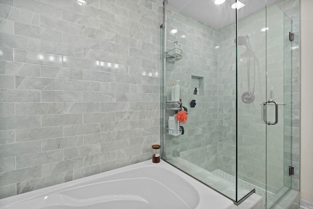 bathroom featuring a stall shower and a bath