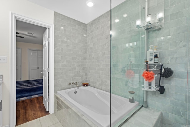 full bathroom with a relaxing tiled tub, tile patterned flooring, and a tile shower