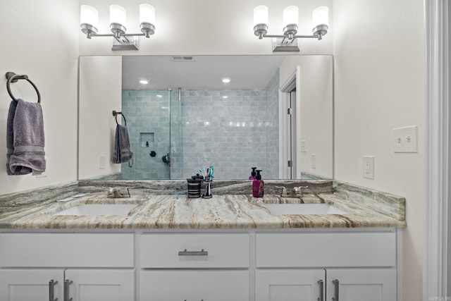 full bath featuring visible vents, a sink, a shower stall, and double vanity