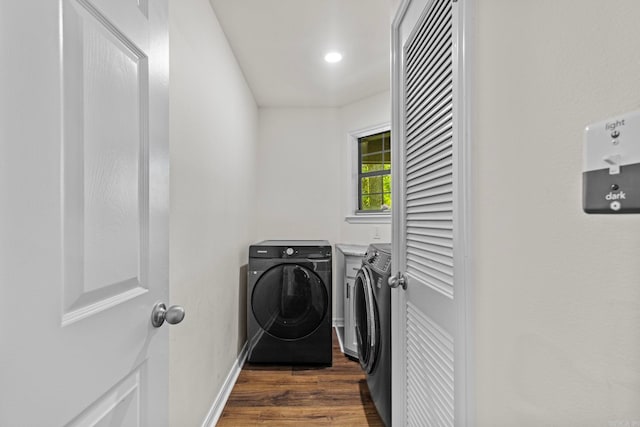 clothes washing area featuring dark wood-type flooring, laundry area, baseboards, and washing machine and clothes dryer