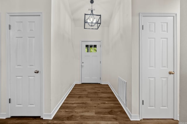 entryway with dark wood-style floors, a chandelier, visible vents, and baseboards