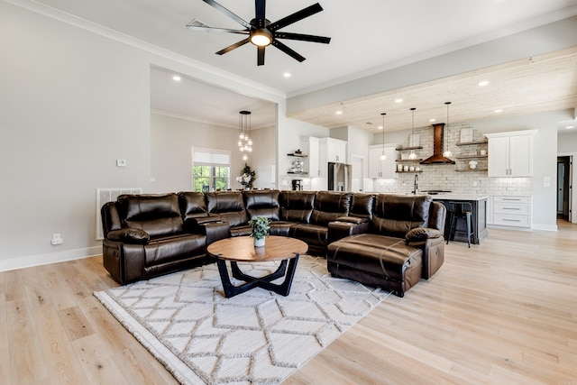 living area featuring recessed lighting, ornamental molding, light wood-type flooring, baseboards, and ceiling fan with notable chandelier