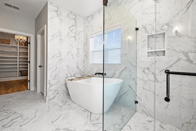 full bathroom featuring a soaking tub, a spacious closet, a marble finish shower, and visible vents